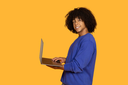 Smiling Young Man Using Laptop Against Yellow Background