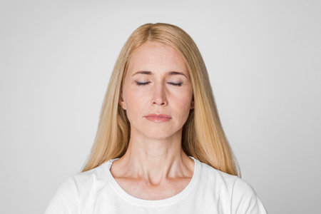 Blonde Woman With Closed Eyes Against a White Backgroundの写真素材