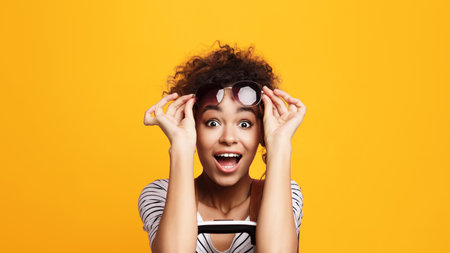 Excited Young Woman With Curly Hair Raising Eyeglassesの写真素材