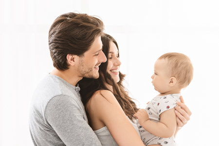 Happy Family Holding Baby Boy Against White Background Indoors
