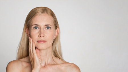 Closeup Portrait of Blonde Woman Touching Face Over White Backgroundの写真素材