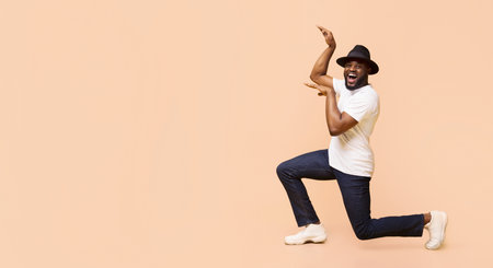 Excited Man in Hat Kneeling and Pointing Towards Copy Space