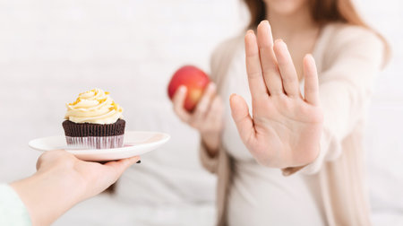 Pregnant woman refusing croissant and choosing fresh appleの写真素材