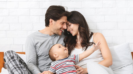 Happy Loving Couple With Baby In Bedroom