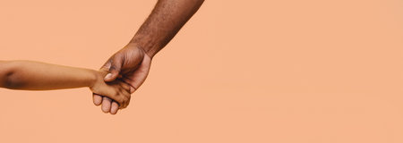 Closeup of Two Hands Holding Together Against Peach Background, Panoramaの写真素材