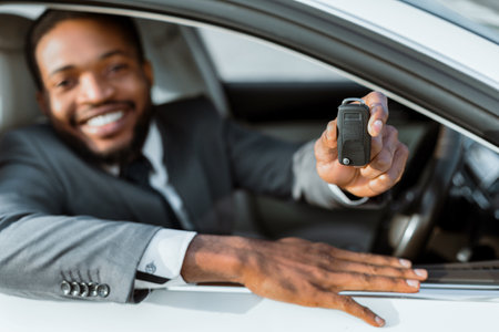 Happy Black Man Showing Car Key From Inside White Carの写真素材