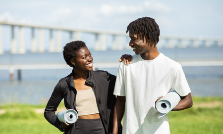 Couple Walking Towards a Bridge With Yoga Mats in Hand