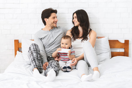 Happy Family Sitting Together On Bed In Pajamasの写真素材