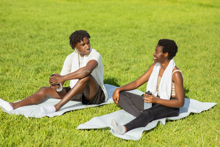 Couple Relaxing On A Green Grass Field After Workoutの写真素材