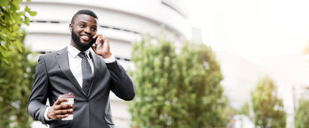 African American employee talking on mobile phone having coffee breakの写真素材