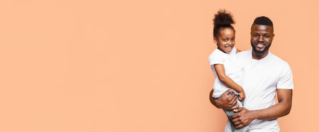 Happy Black Father And Daughter Smiling Against Peach Backgroundの写真素材