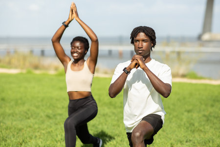 Man and Woman Performing Yoga Poses in a Green Parkの写真素材