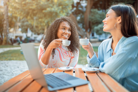 Two Women Enjoying Coffee and Conversation at an Outdoor Cafeの写真素材