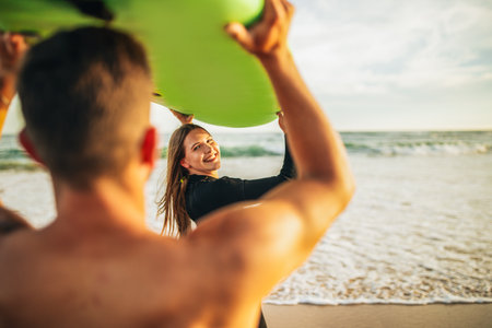 Couple Holding Green Surfboard on a Sandy Beach at Sunset