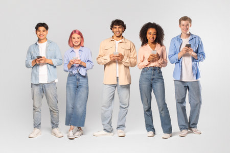 Diverse Group of Young Adults Using Smartphones Against White Background