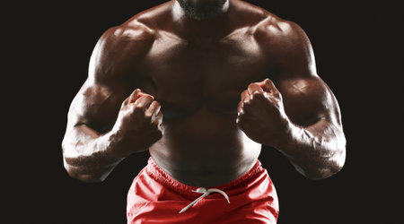 Muscular Man Flexing Biceps Against Black Background