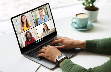 Black Man Participating in Video Conference on Laptop at Tableの写真素材