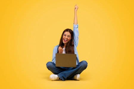 Cheerful young european student woman with laptop, rise hand upの写真素材