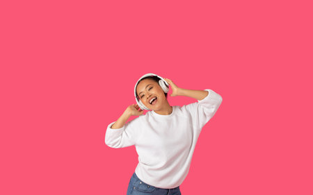 Happy Young Woman Dancing With Headphones on Pink Background