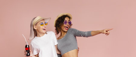 Two Women Laughing Together In Summer Outfits Against Pink Background