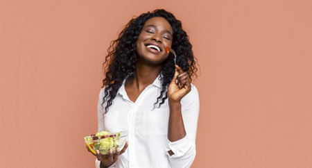 Happy Woman Enjoying Fresh Salad Against Peach Backgroundの写真素材