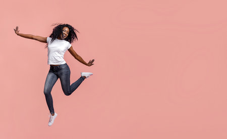 Happy Woman Jumping in Front of Pink Backgroundの写真素材
