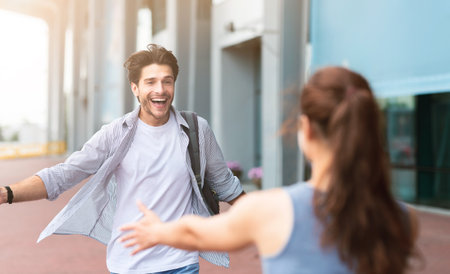 Man greeting girlfriend after arriving to airport, spreading hands for embraceの写真素材