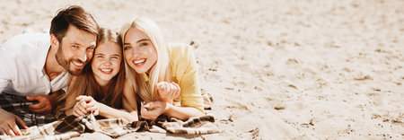 Happy parents and daughter lying together on picnic blanketの写真素材