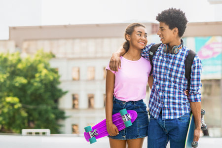 Teen Black Couple Walking With Skateboard in Urban Settingの写真素材