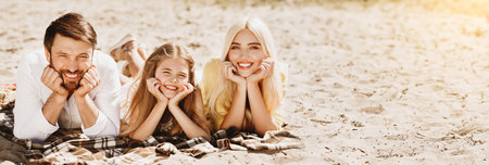 Young family lying on blanket and smiling to cameraの写真素材