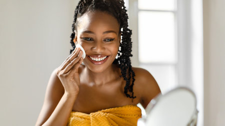 Smiling Woman Applying Facial Cleanser in Bathroom Mirrorの写真素材