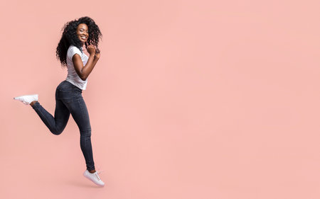 Smiling Woman Jumping in Front of Pink Background