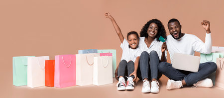 Happy black family with laptop, credit card and shopping bags.の写真素材