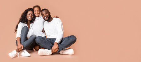 Afro millennial family of three sitting on floor and hugging