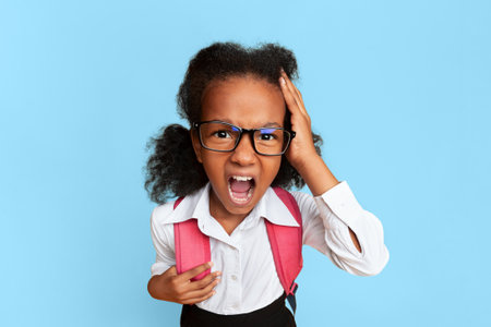 Little School Girl Shouting Touching Head On Yellow Backgroundの写真素材