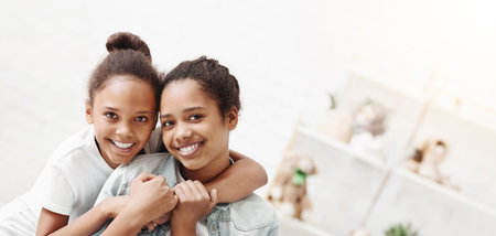 Portrait of two lovely african sisters bonding at homeの写真素材