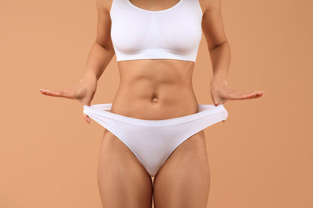 Woman Wearing White Underwear, Sports Bra Posing Against Tan Backgroundの写真素材
