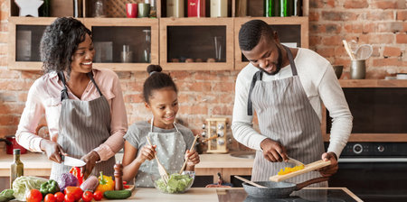 Mom and daughter watching dad while cooking togetherの写真素材