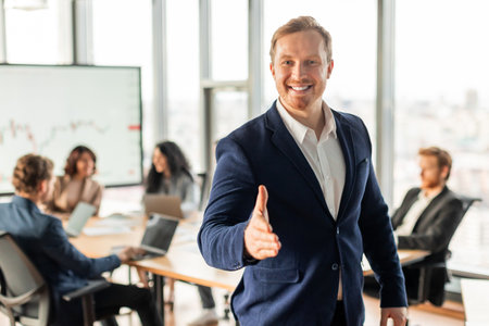 Smiling Businessman Extends Hand for Handshake During Meeting in Officeの写真素材