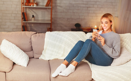 Couple Using Tablet And Smartphone Sitting On Couch At Homeの写真素材