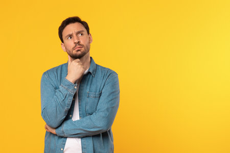 A Man Thinking and Looking Upward on Yellow Backgroundの写真素材