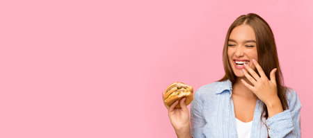 Happy Girl Eating Burger Laughing On Yellow Studio Background, Panoramaの写真素材