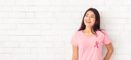 Asian Girl With Awareness Cancer Ribbon Posing Over White Wallの写真素材