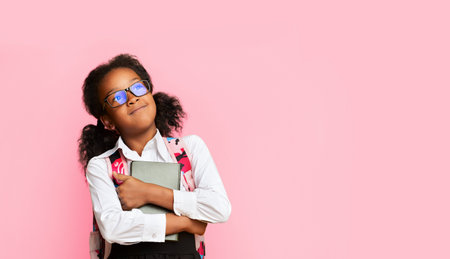 Happy African Schoolgirl Hugging Book, Studio Shot, Copy Spaceの写真素材