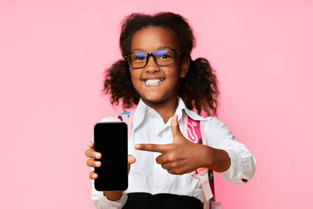 African Schoolgirl Showing Blank Phone Screen Over Yellow Background, Mockupの写真素材