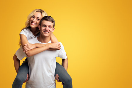 Smiling young guy carrying girlfriend on his backの写真素材