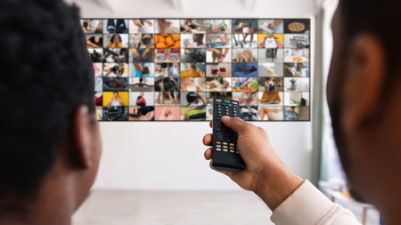 Man Using Remote Control to Change Channels on Televisionの写真素材