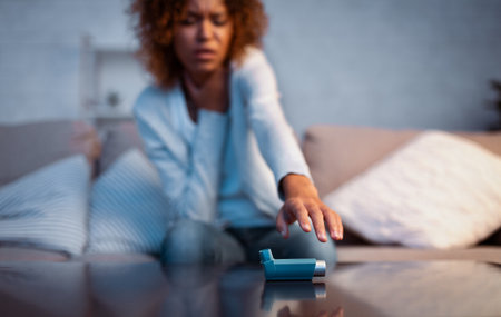 Asthma attack. Young woman reaching inhaler on tableの写真素材