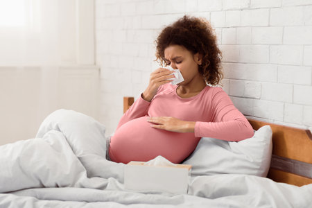 Pregnancy and illness. Sick woman blowing nose in tissue