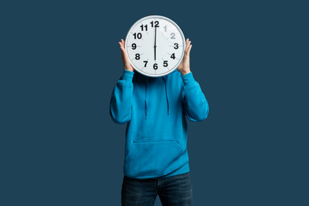 Young Person Holding Large Wall Clock in Front of Faceの写真素材